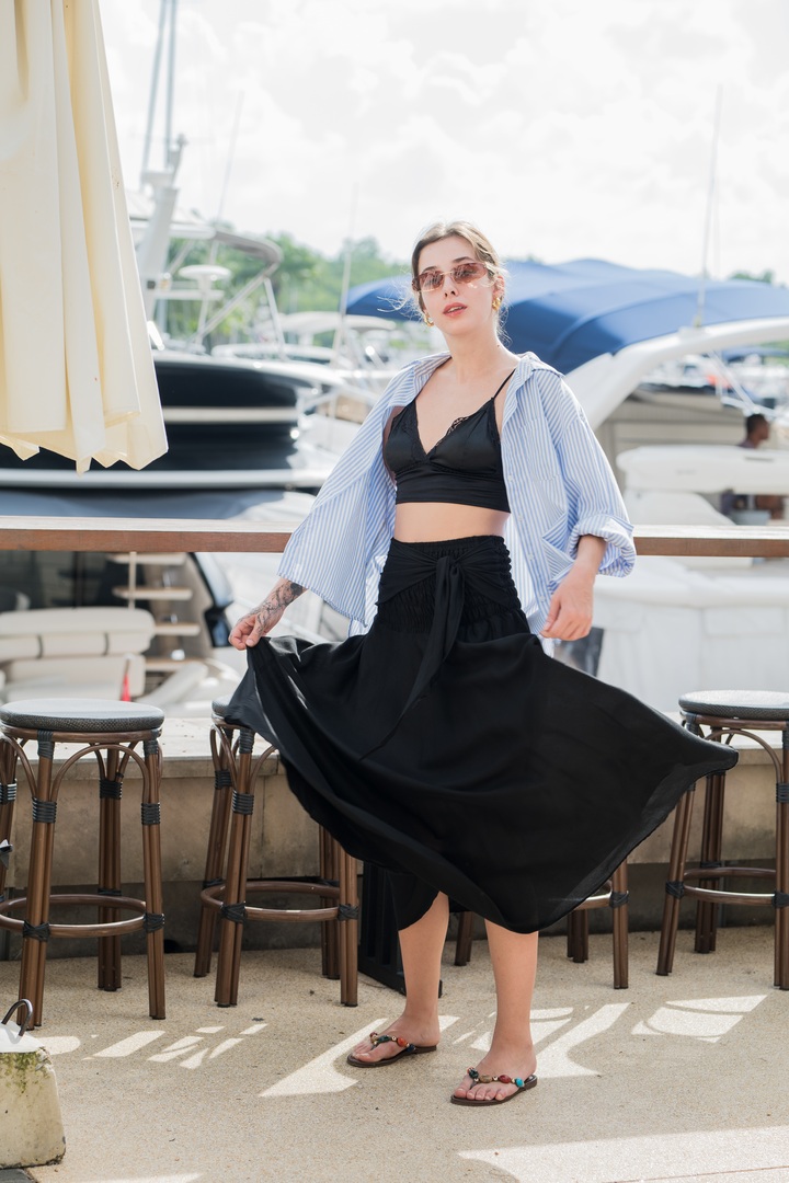 Creator wearing a flowing black skirt beside a marina