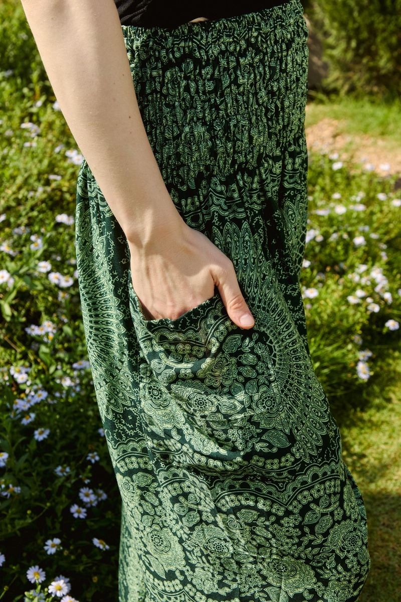 Hand visibly resting inside the pocket of green patterned pants